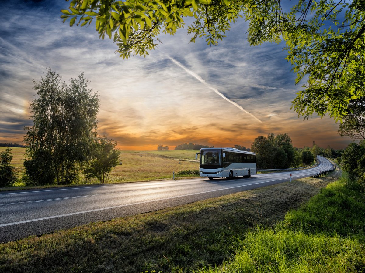 A coach travelling along a rural road at sunset